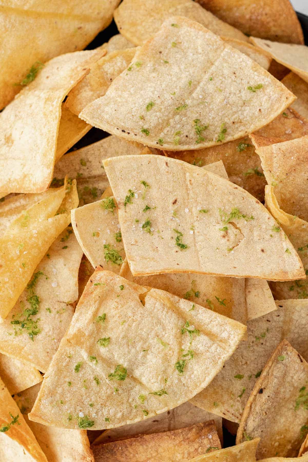 Closeup of air fryer tortilla chips seasoned with sea salt and lime zest.