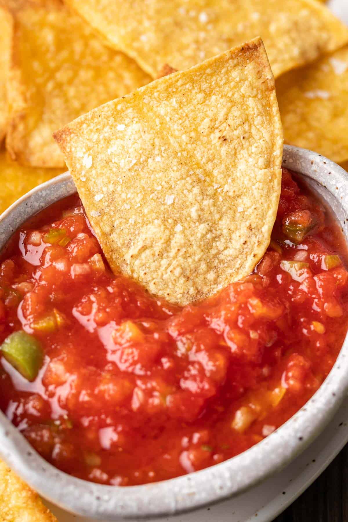 Air fryer tortilla chip in a bowl of salsa.