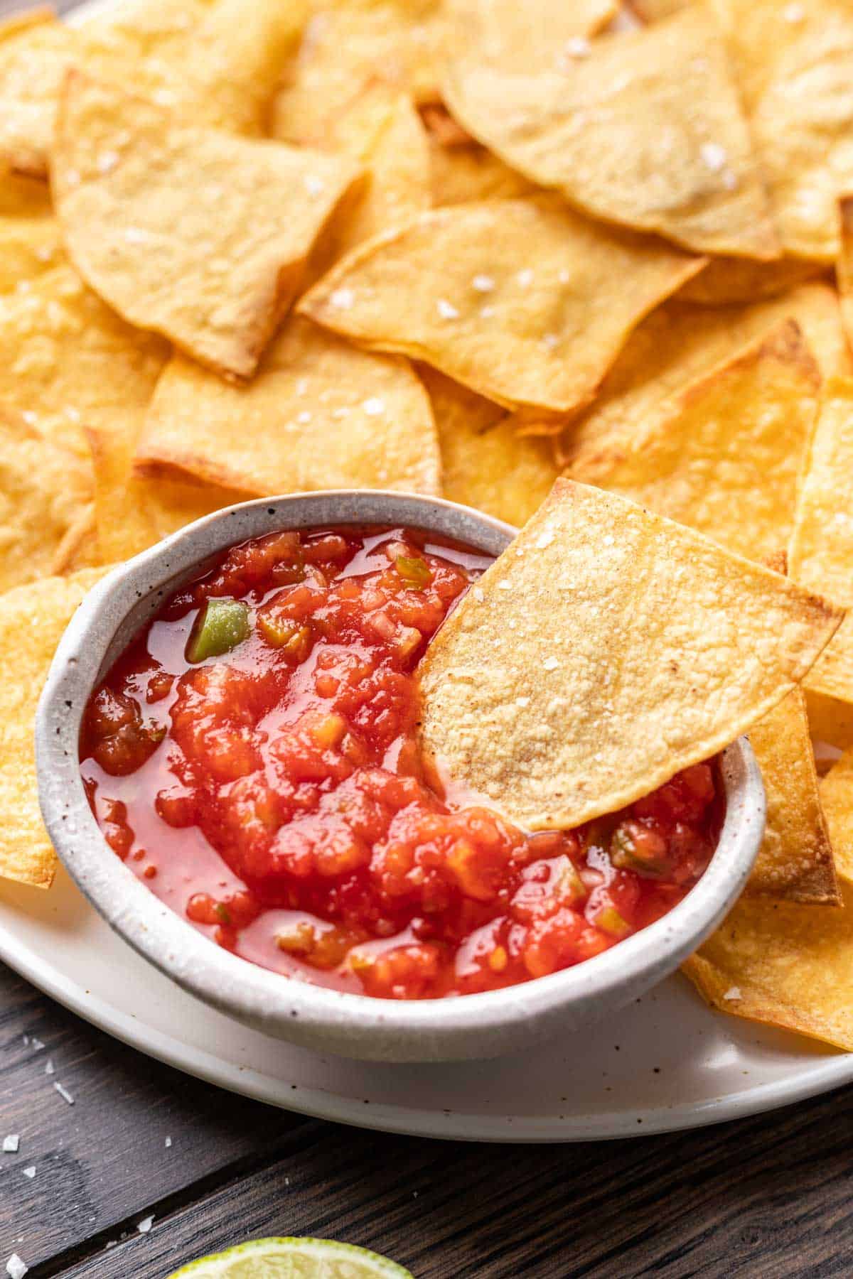 An air fryer tortilla chip dipped in salsa.