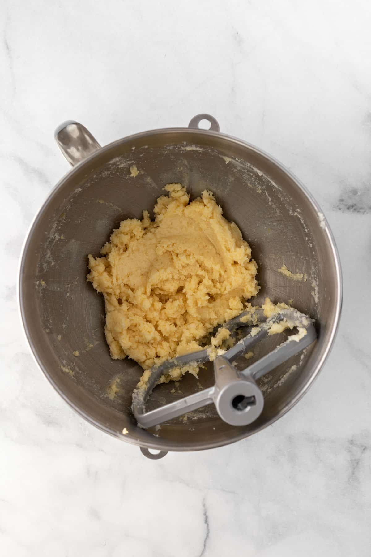 Mixture of butter, sugar, egg, vanilla extract, and almond extract in a metal bowl.