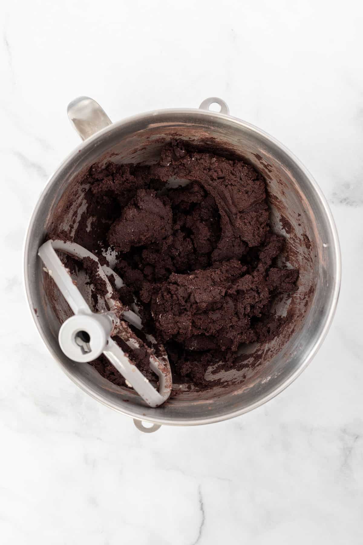 Fully combined chocolate hamantaschen dough in a metal bowl.