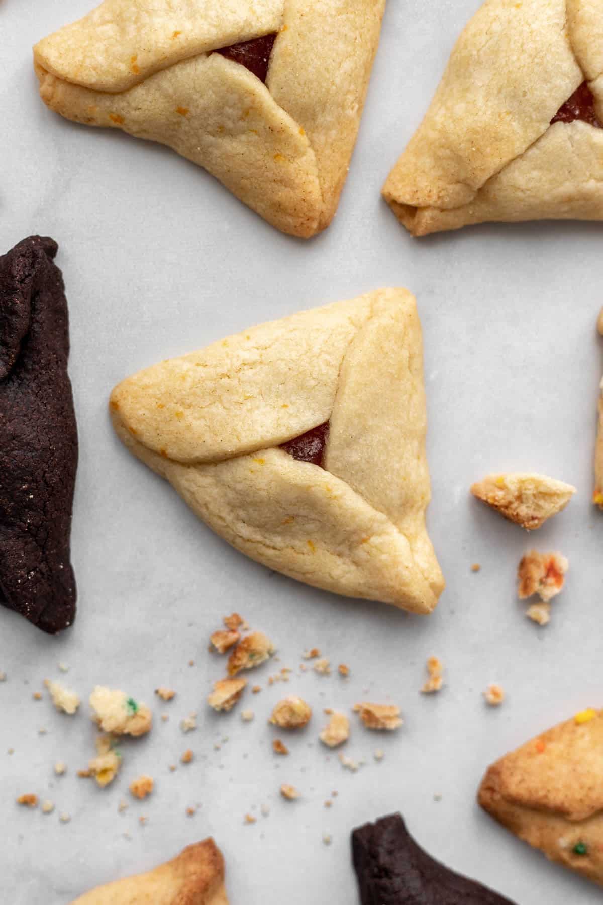 An orange marmalade hamantaschen surrounded by chocolate peanut butter and cinnamon apple hamantaschen.