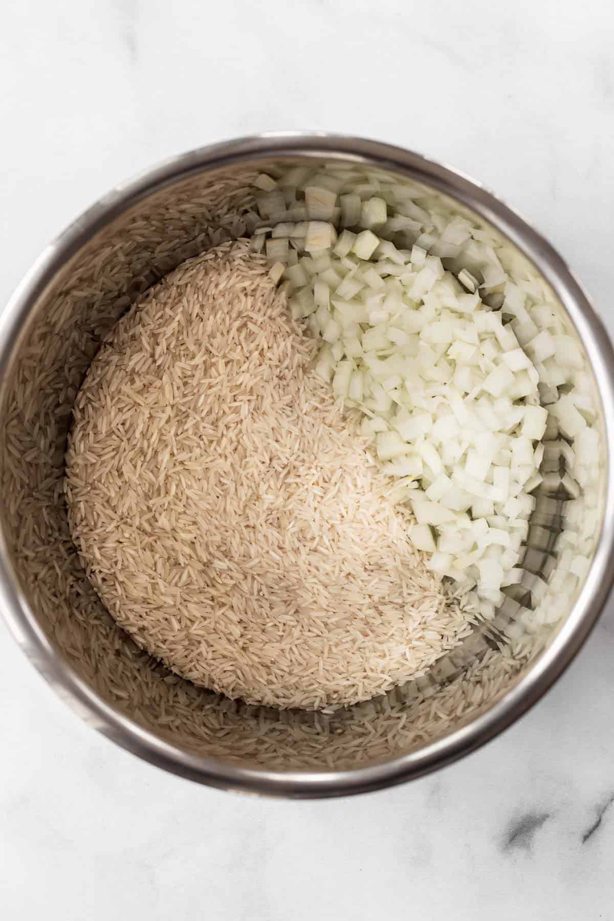 Chopped onions and basmati rice in an instant pot.