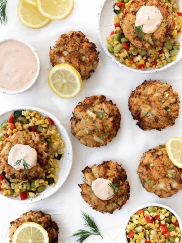 Air fryer crab cakes served with corn succotash, remoulade sauce, lemon slices, and fresh dill.