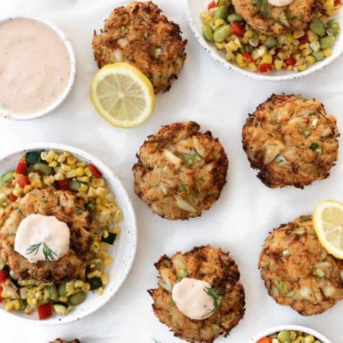 Air fryer crab cakes served with corn succotash, remoulade sauce, lemon slices, and fresh dill.