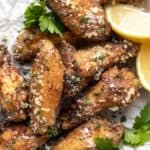 A closeup of air fryer chicken wings topped with parmesan cheese and parsley.