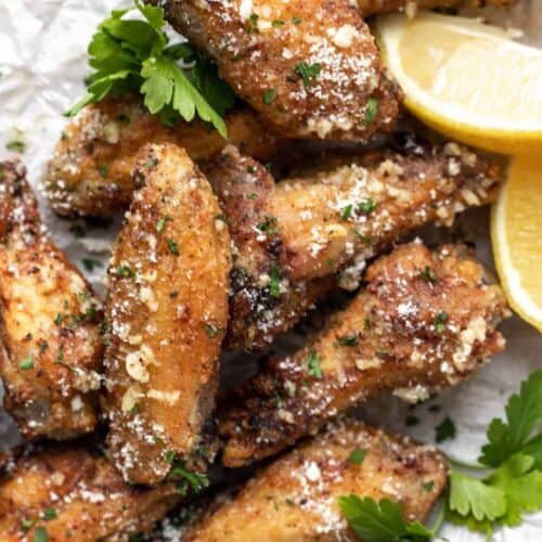 A closeup of air fryer chicken wings topped with parmesan cheese and parsley.