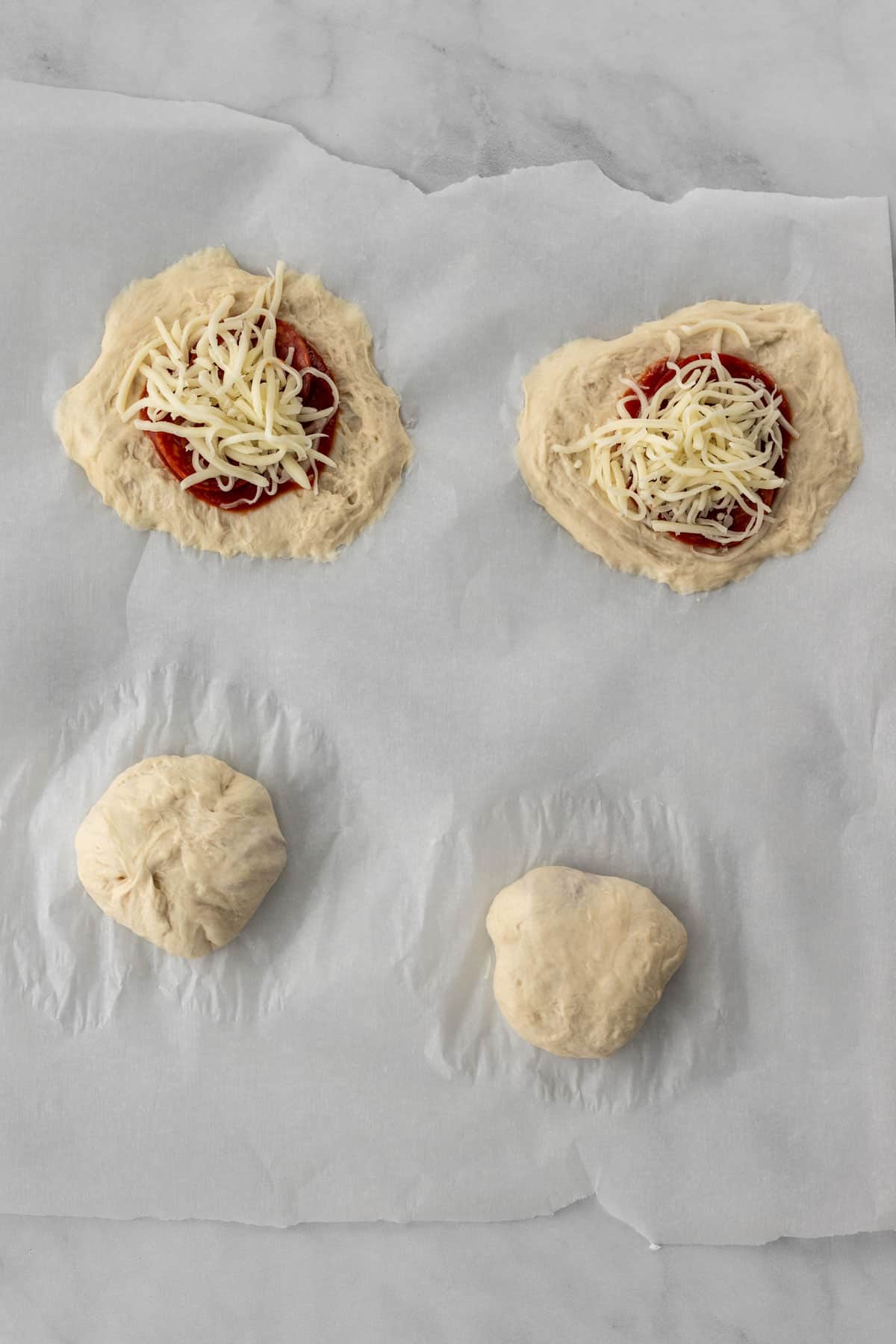 2 flattened doughs with all the toppings and 2 rolled balls of dough with the toppings inside.