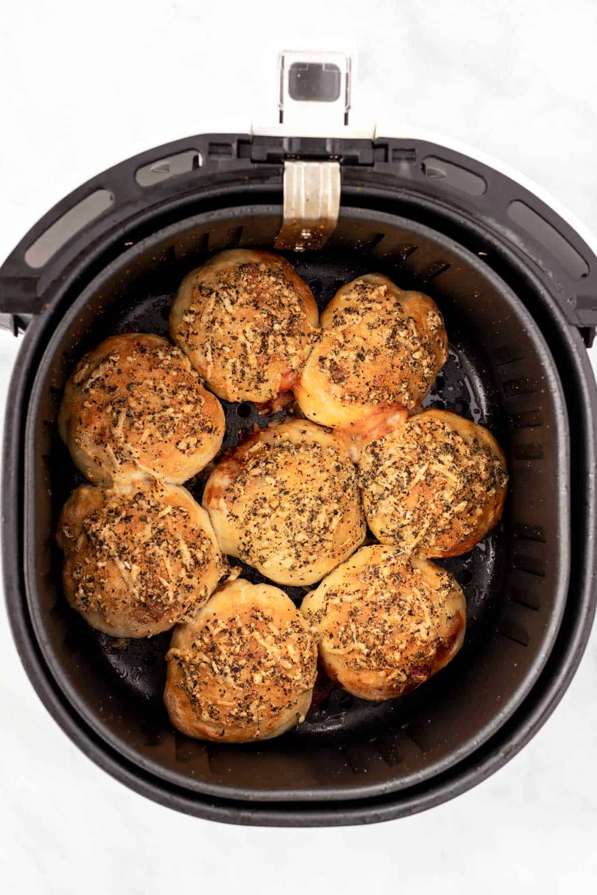 Cooked golden brown pizza rolls in the air fryer basket.