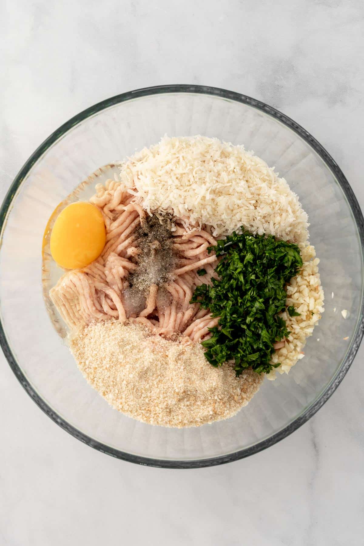 All the meatball ingredients in a glass bowl.