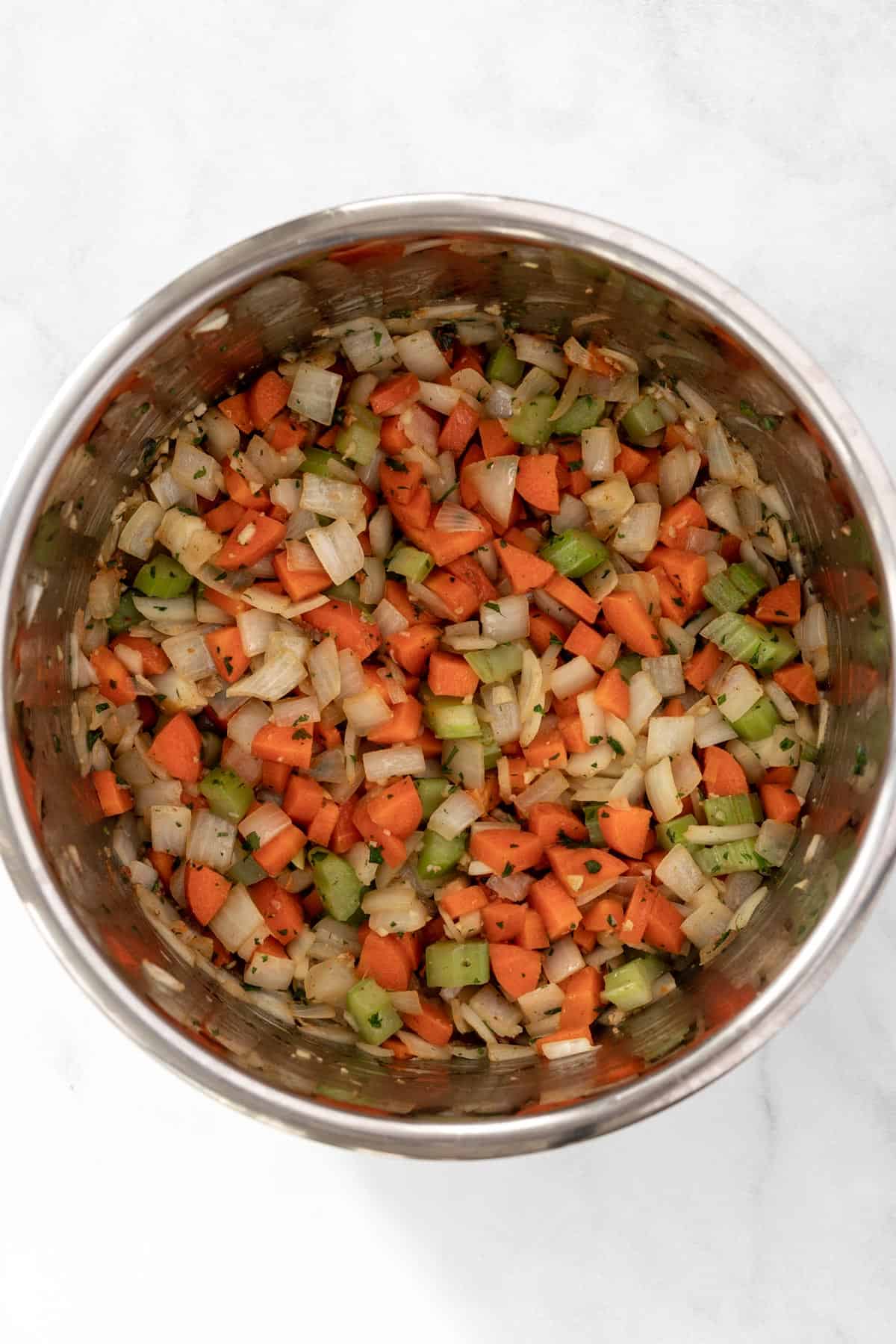 Chopped onions, carrots, and celery in the pot of an instant pot.