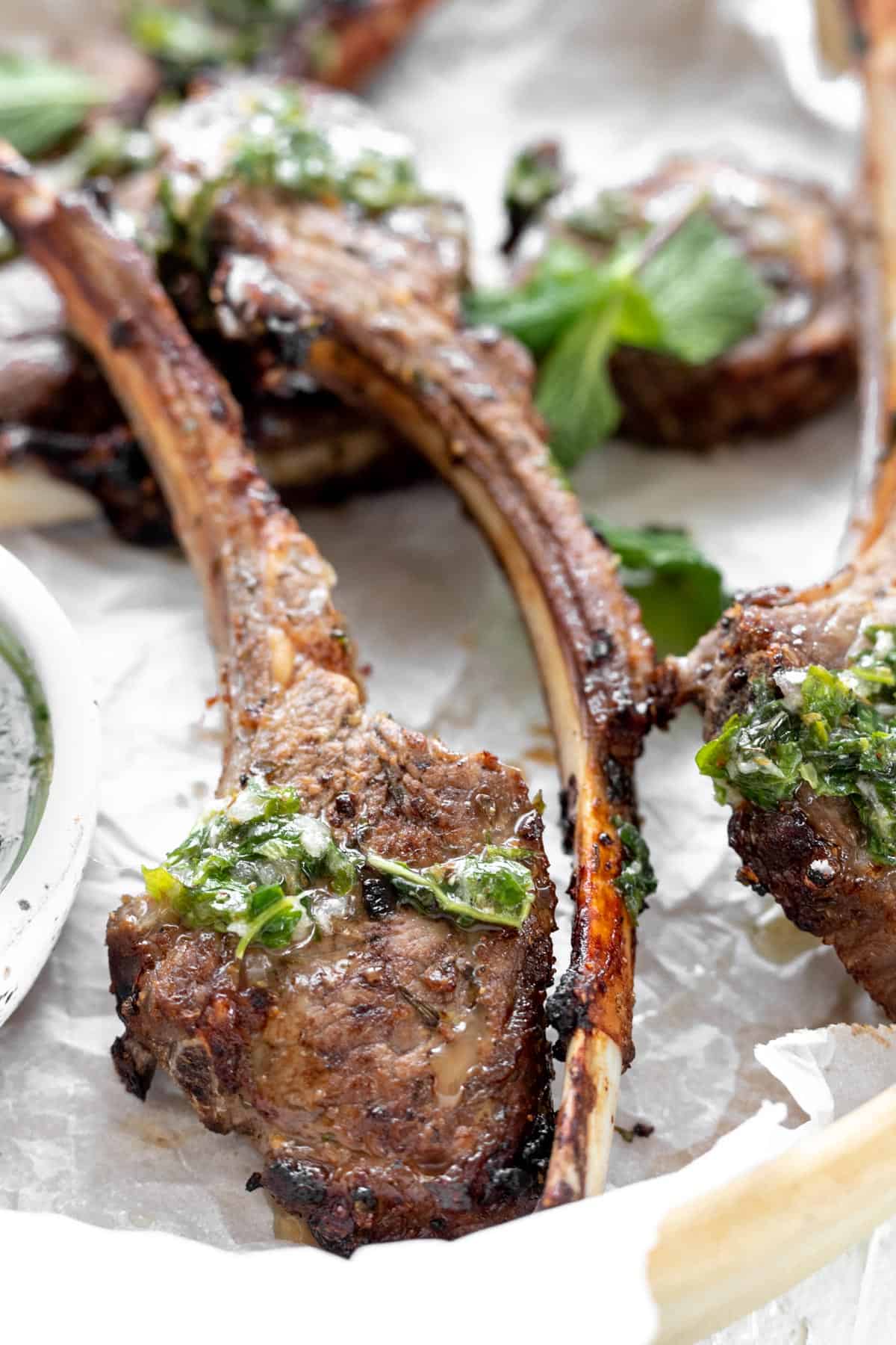 A closeup shot of a lamb chop with mint chimichurri drizzled on top.