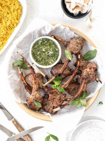 Air fryer lamb chops in a serving dish with a side of yellow rice and mint chimichurri.