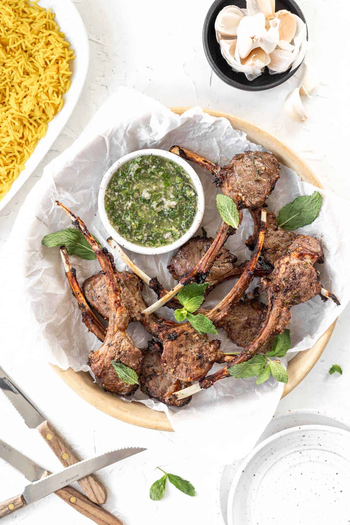 Air fryer lamb chops in a serving dish with a side of yellow rice and mint chimichurri.