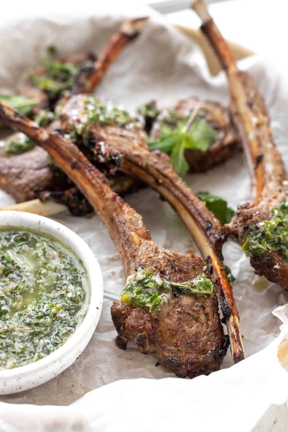 A closeup shot of an air fryer lamb chop with mint chimichurri drizzled on top.