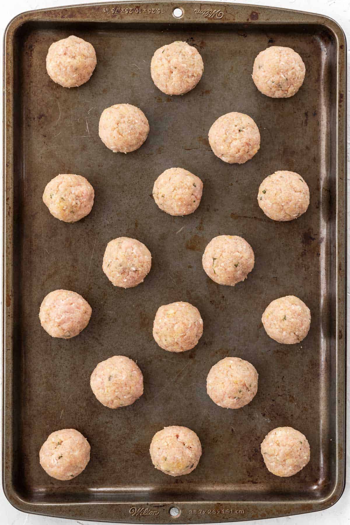 Raw meatballs on a baking sheet.