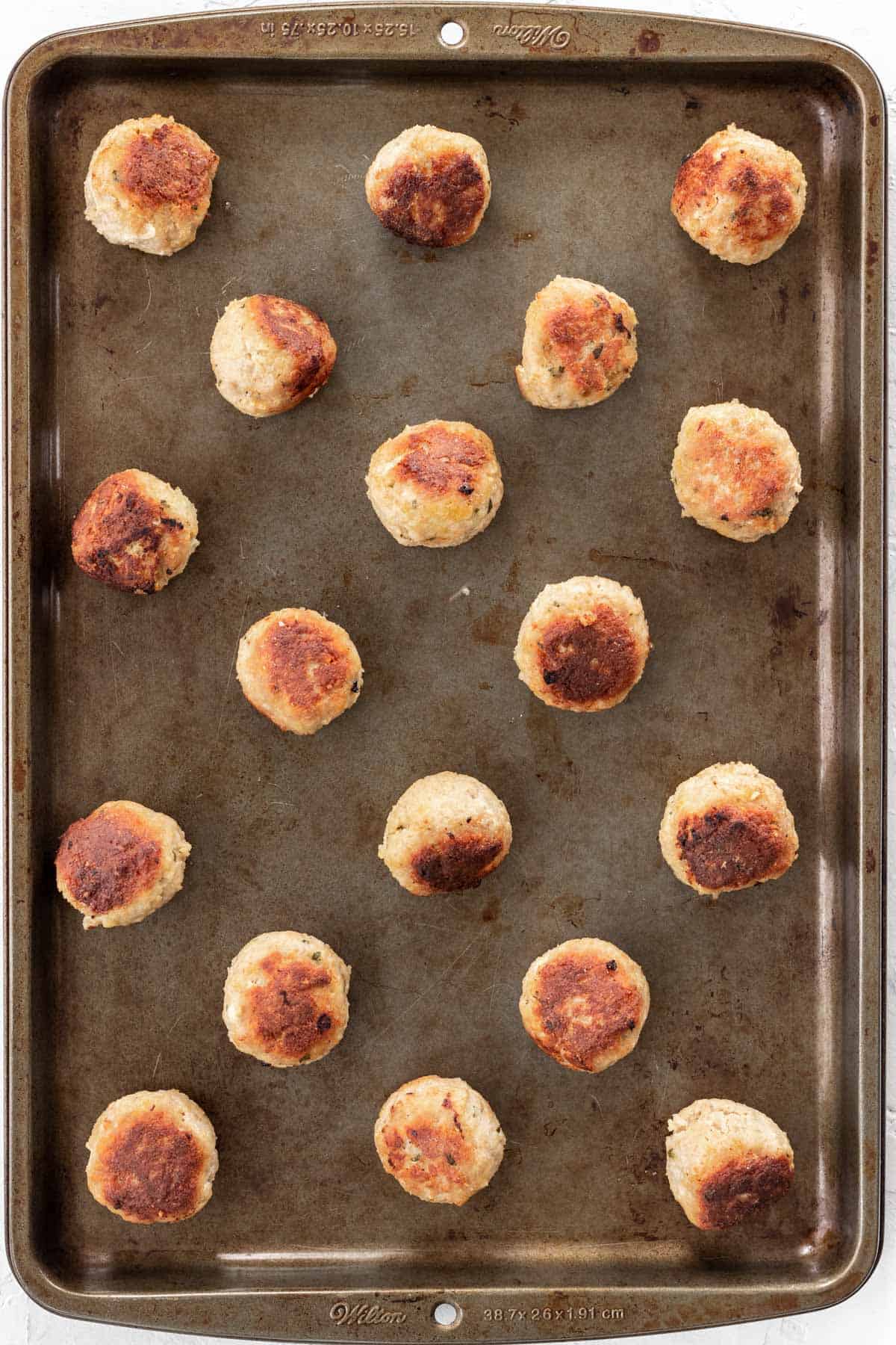 Browned meatballs on a baking sheet.