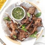 Air fryer lamb chops in a serving dish with a side of chimichurri.
