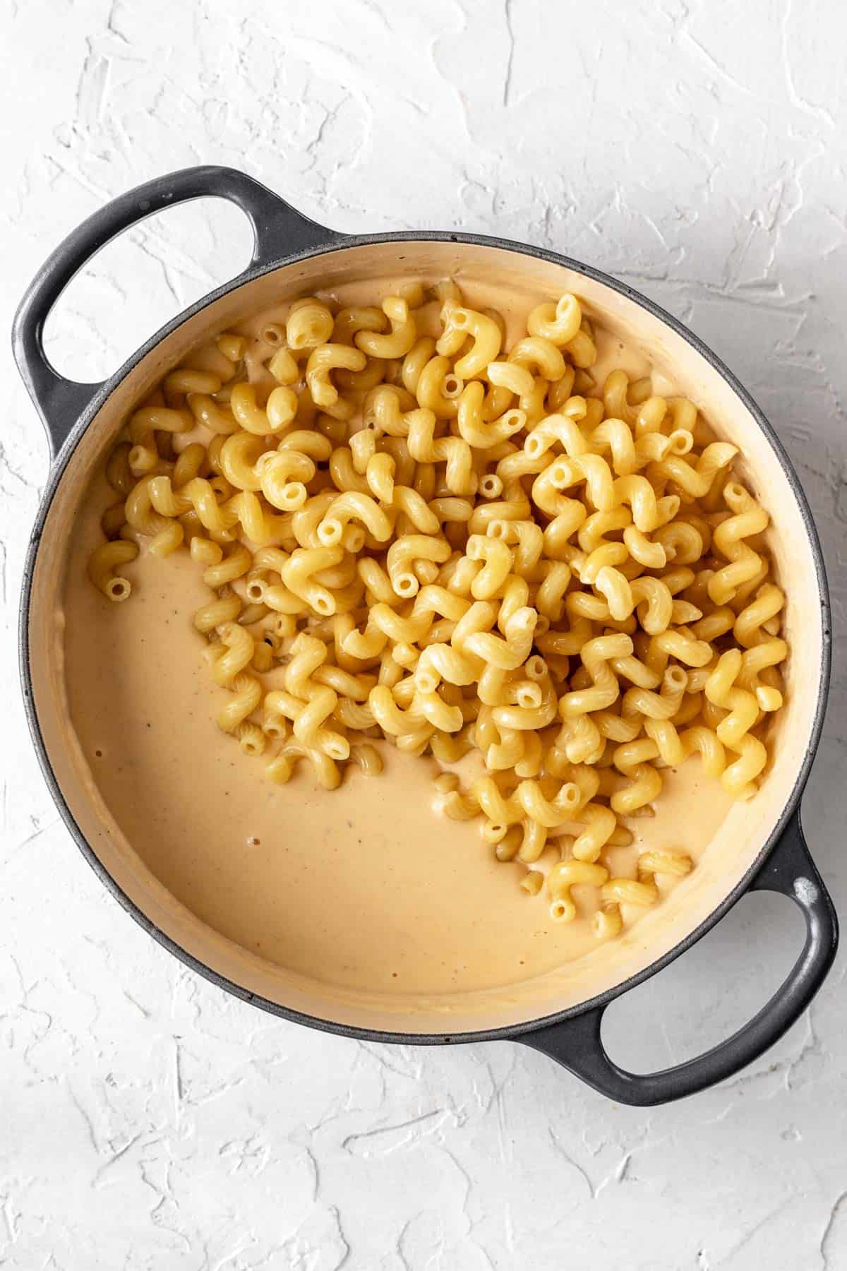 Cooked pasta added to the creamy cheddar cheese sauce.