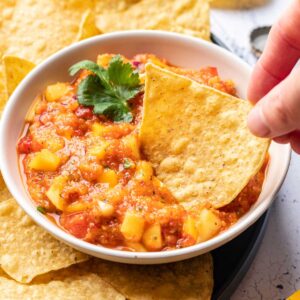 Mango habanero salsa in a bowl with a chip dipped in.