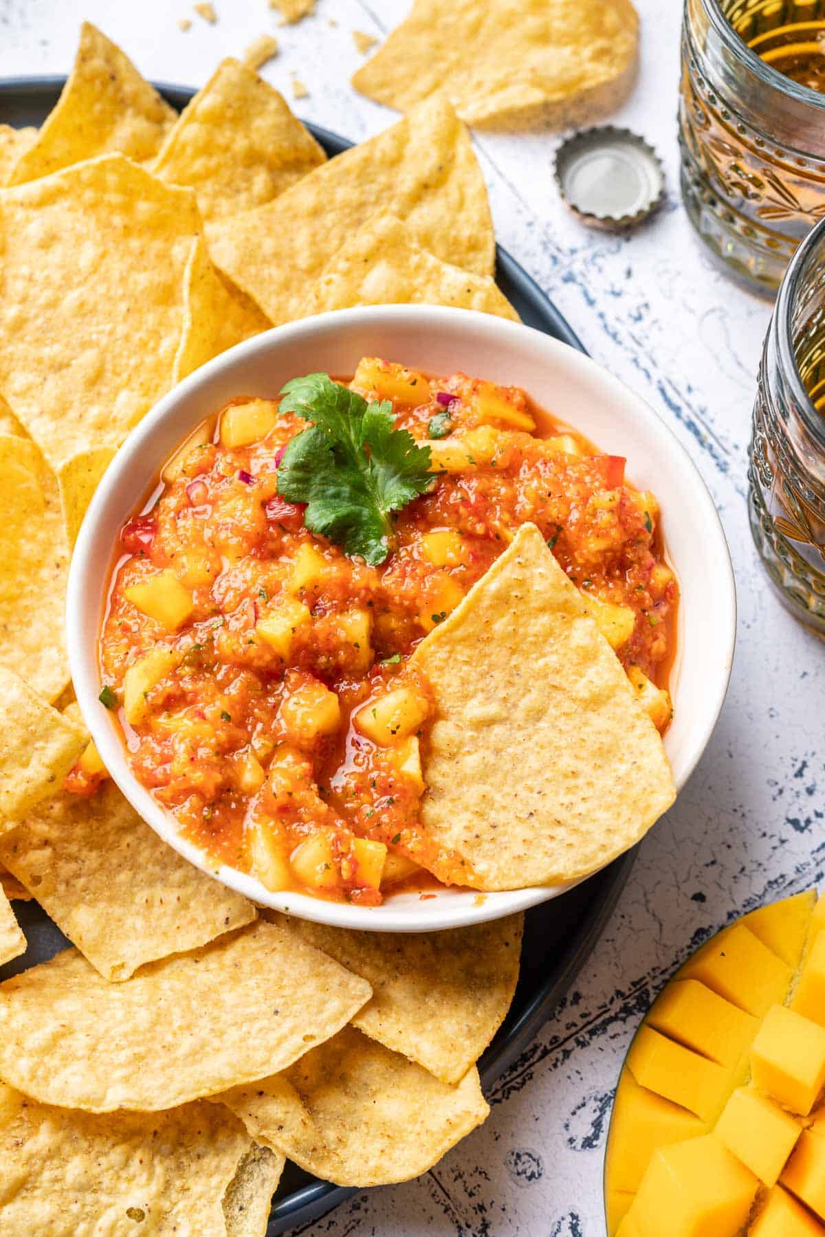 Mango habanero salsa in a bowl a tortilla chip in it.