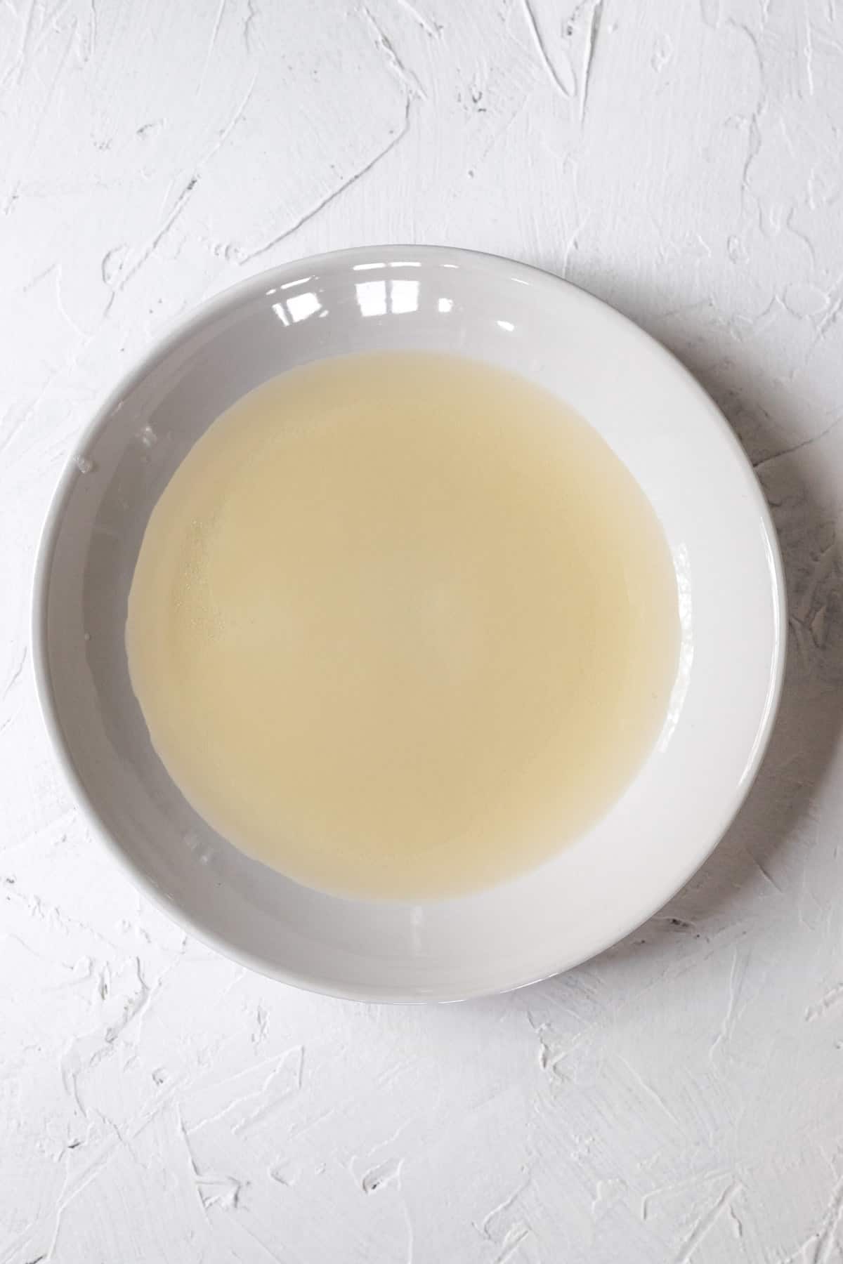 Rice vinegar, sugar, and salt in a microwaveable white bowl.