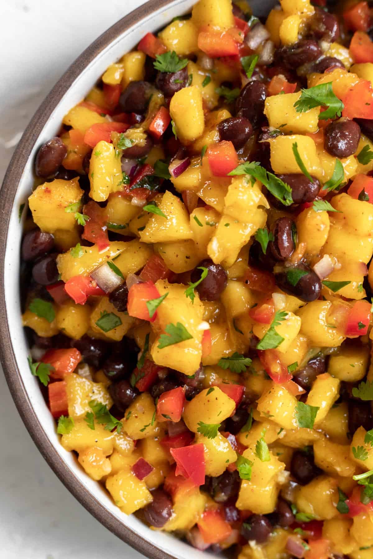 Close up view of mango salsa with black beans in a round serving dish.