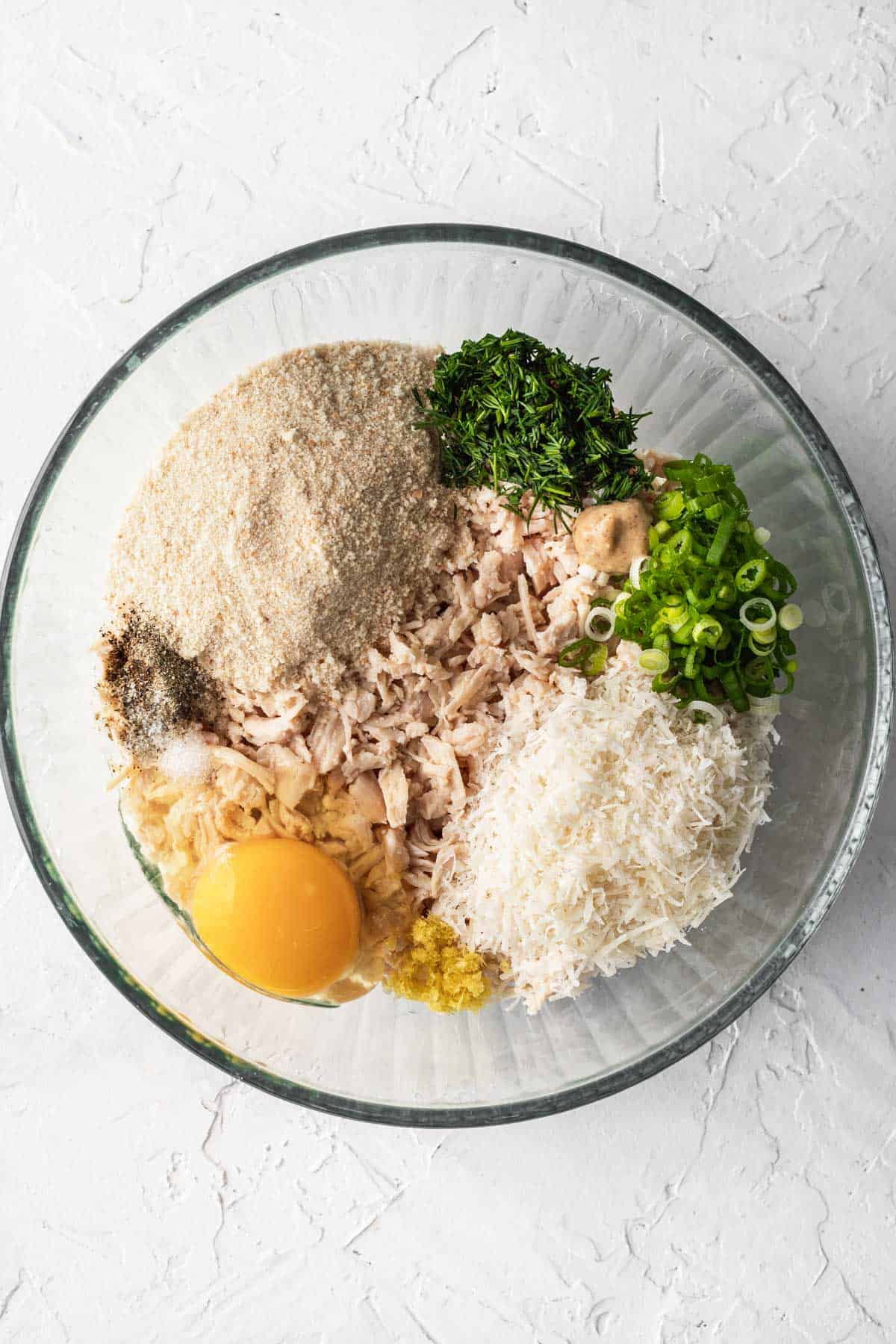 Ingredients for chicken patties in a glass bowl.