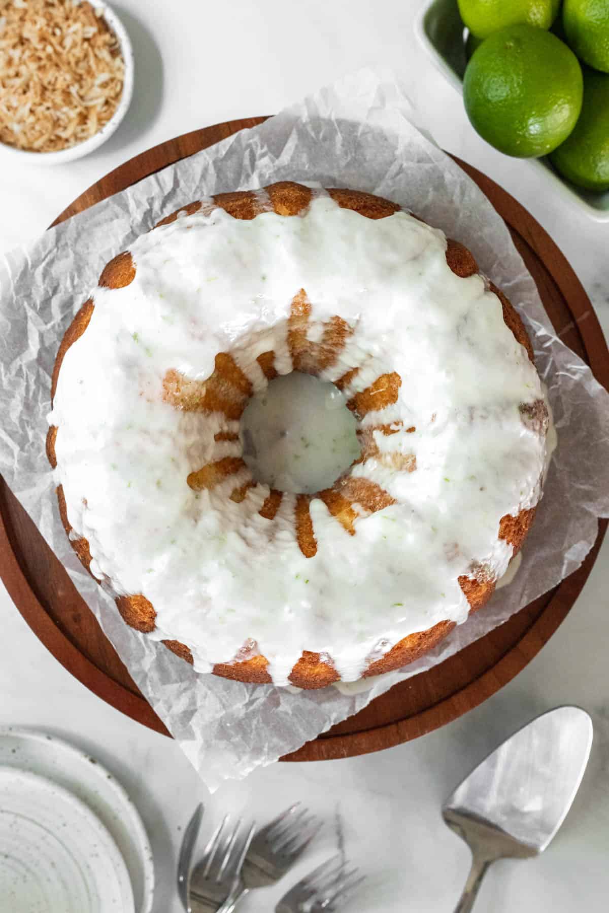 Coconut lime cake on a cake stand and drizzled with glaze.