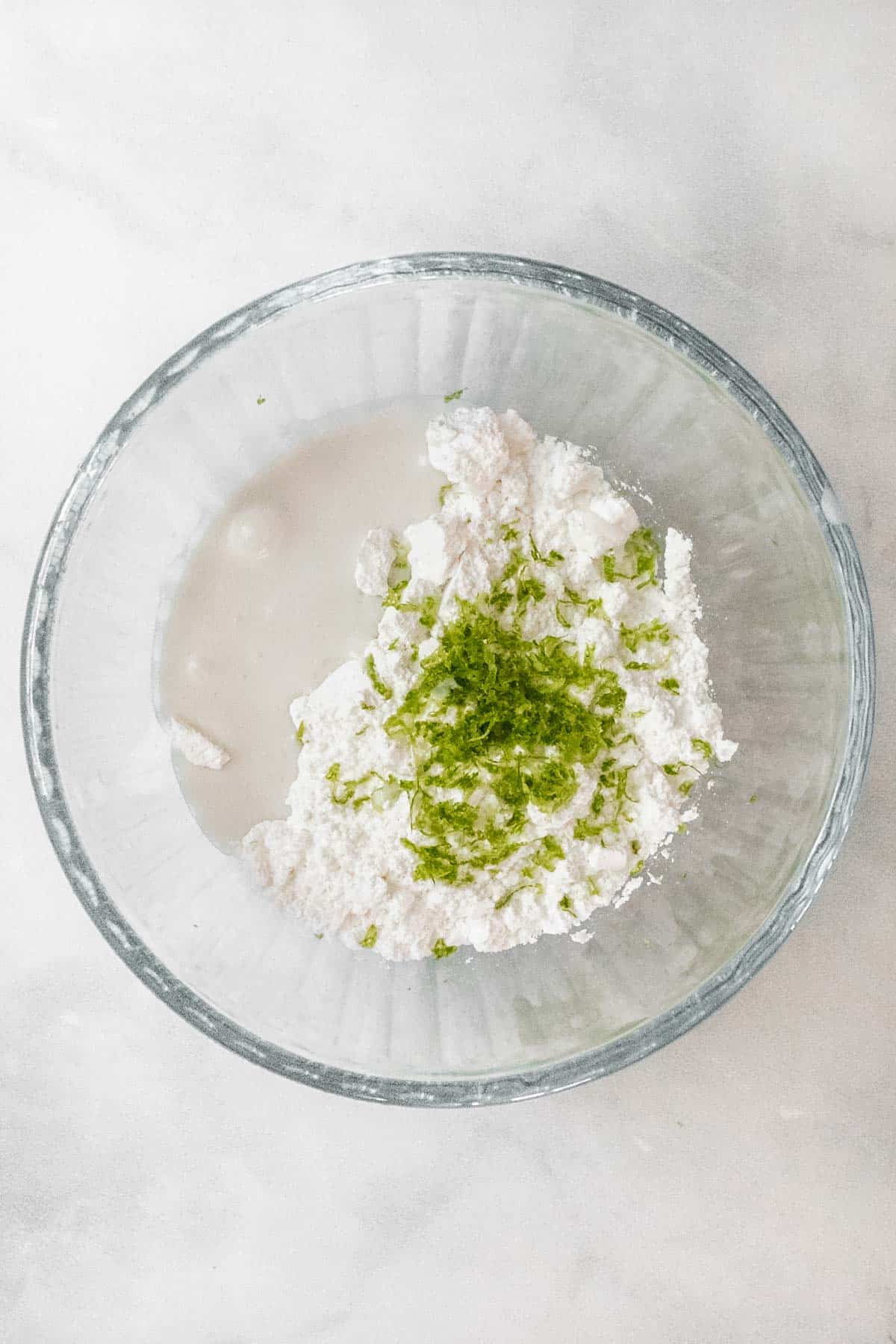 Ingredients for the coconut lime drizzle in a glass mixing bowl.