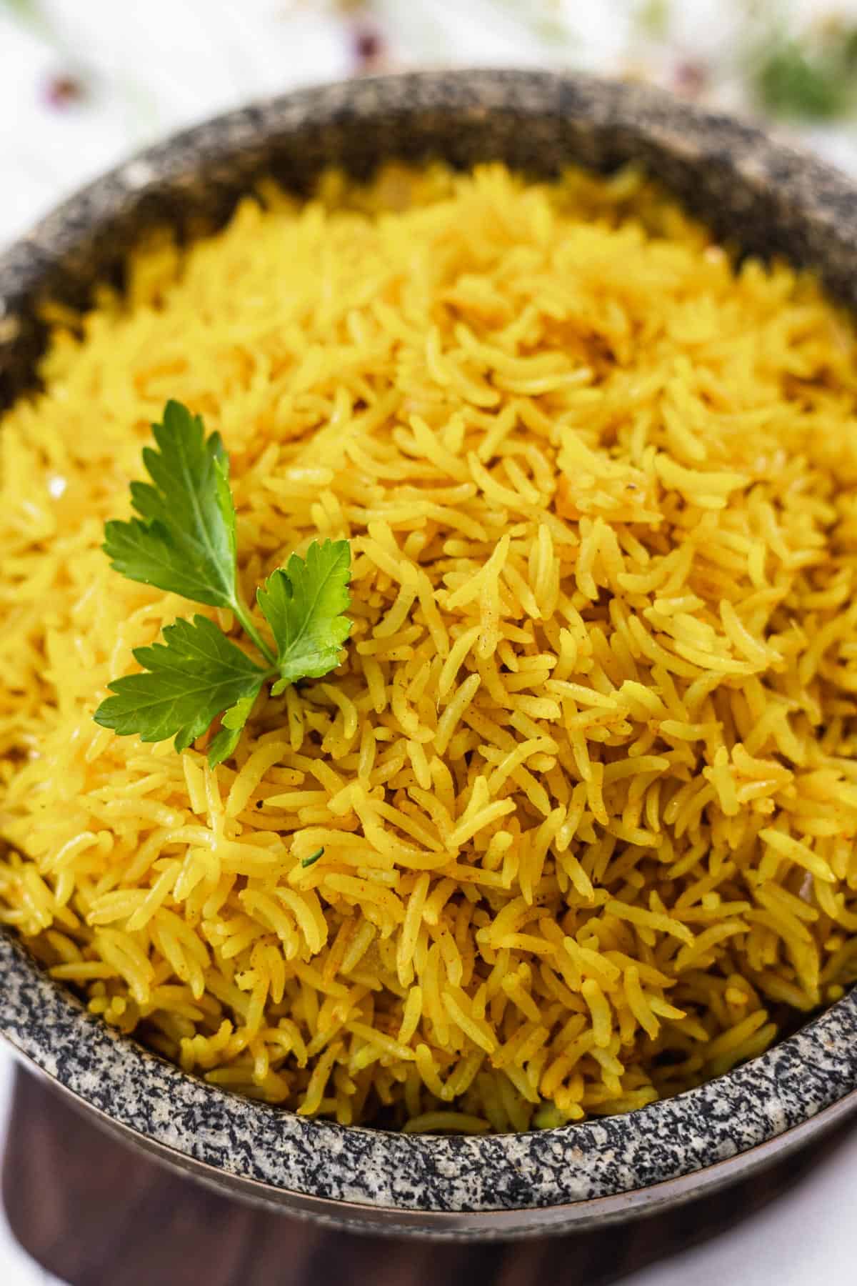 Instant pot yellow rice garnished with parsley in a stone bowl.