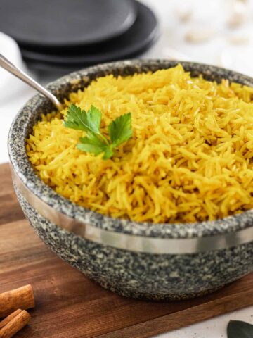 Easy homemade yellow rice in a stone bowl with a serving spoon.
