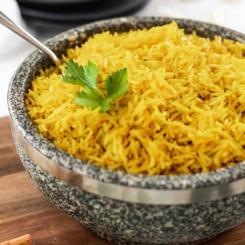 Easy homemade yellow rice in a stone bowl with a serving spoon.