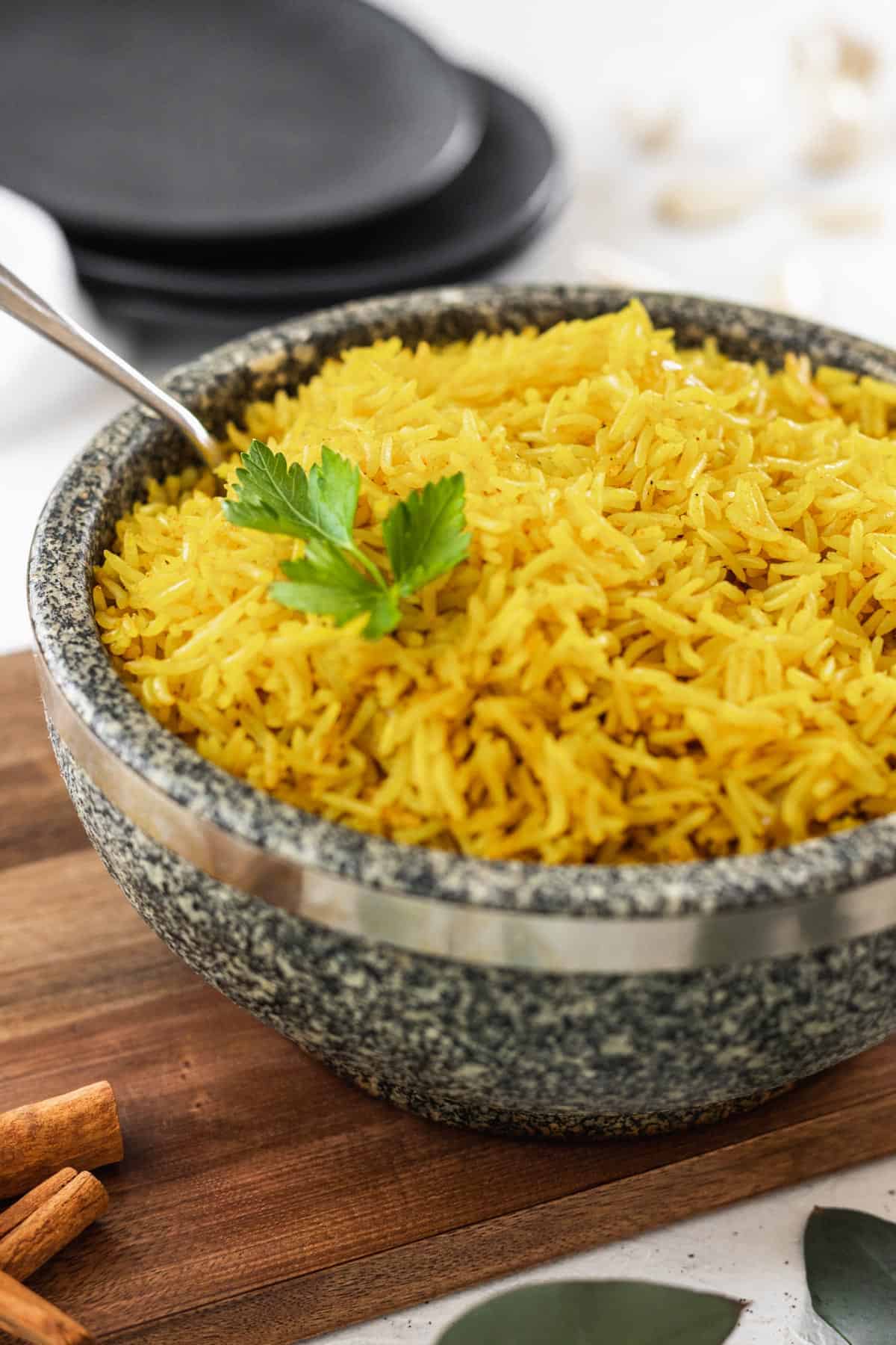 Easy homemade yellow rice in a stone bowl with a serving spoon.