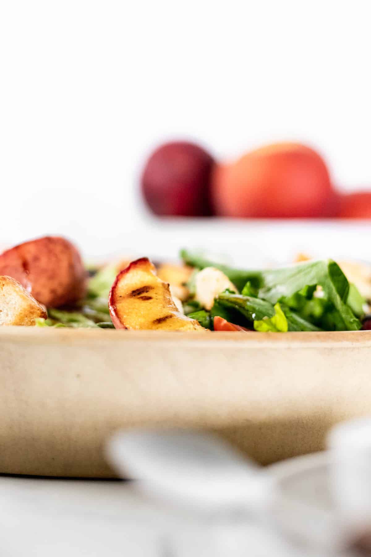 A side view of the summer salad with a grilled peach sticking up.