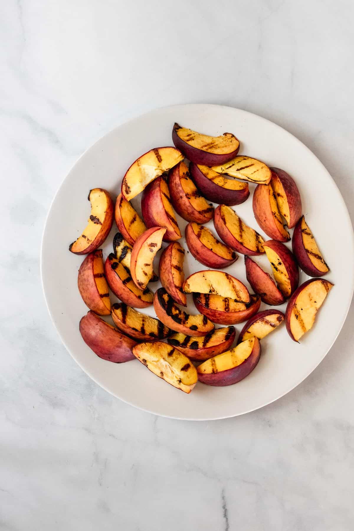 Grilled peach slices on a white plate.