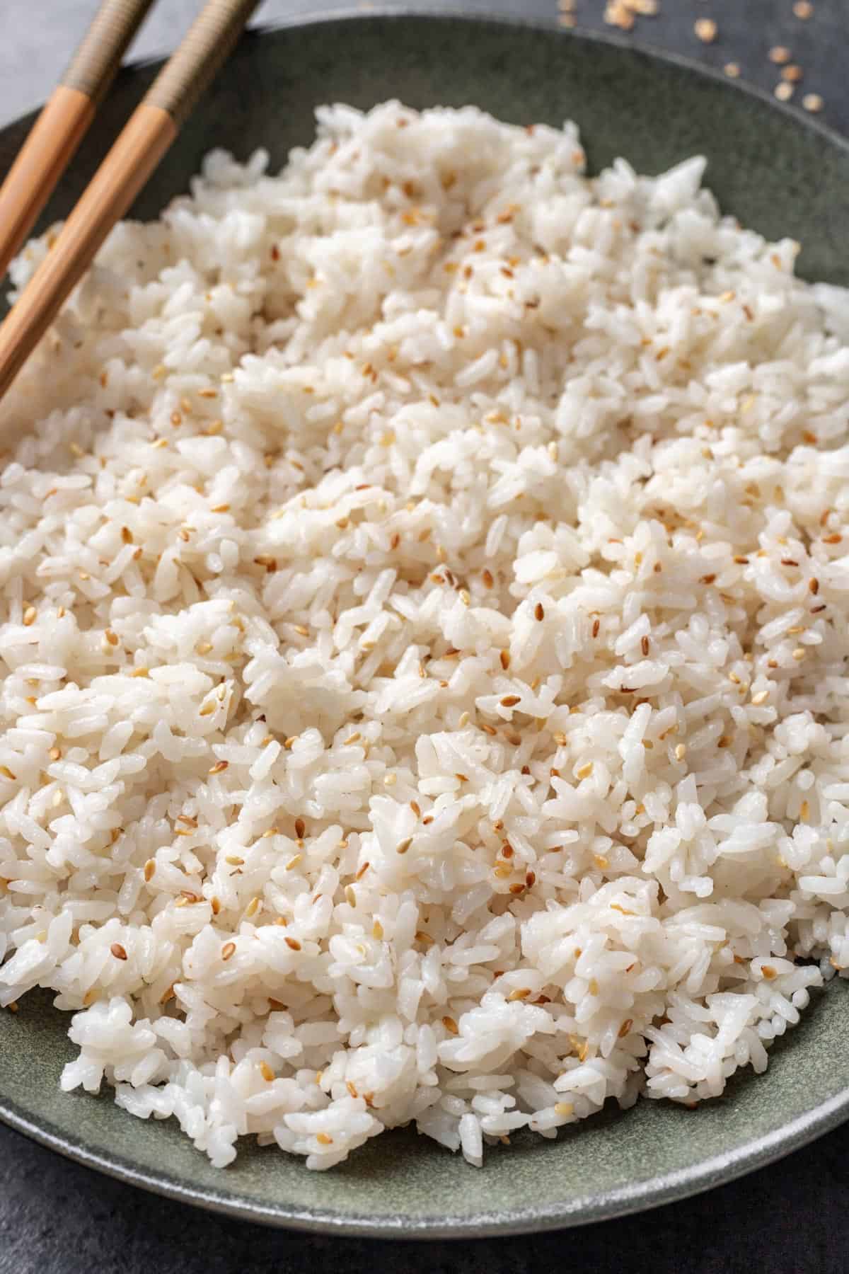 Sushi rice in a serving bowl with toasted sesame seeds mixed in.