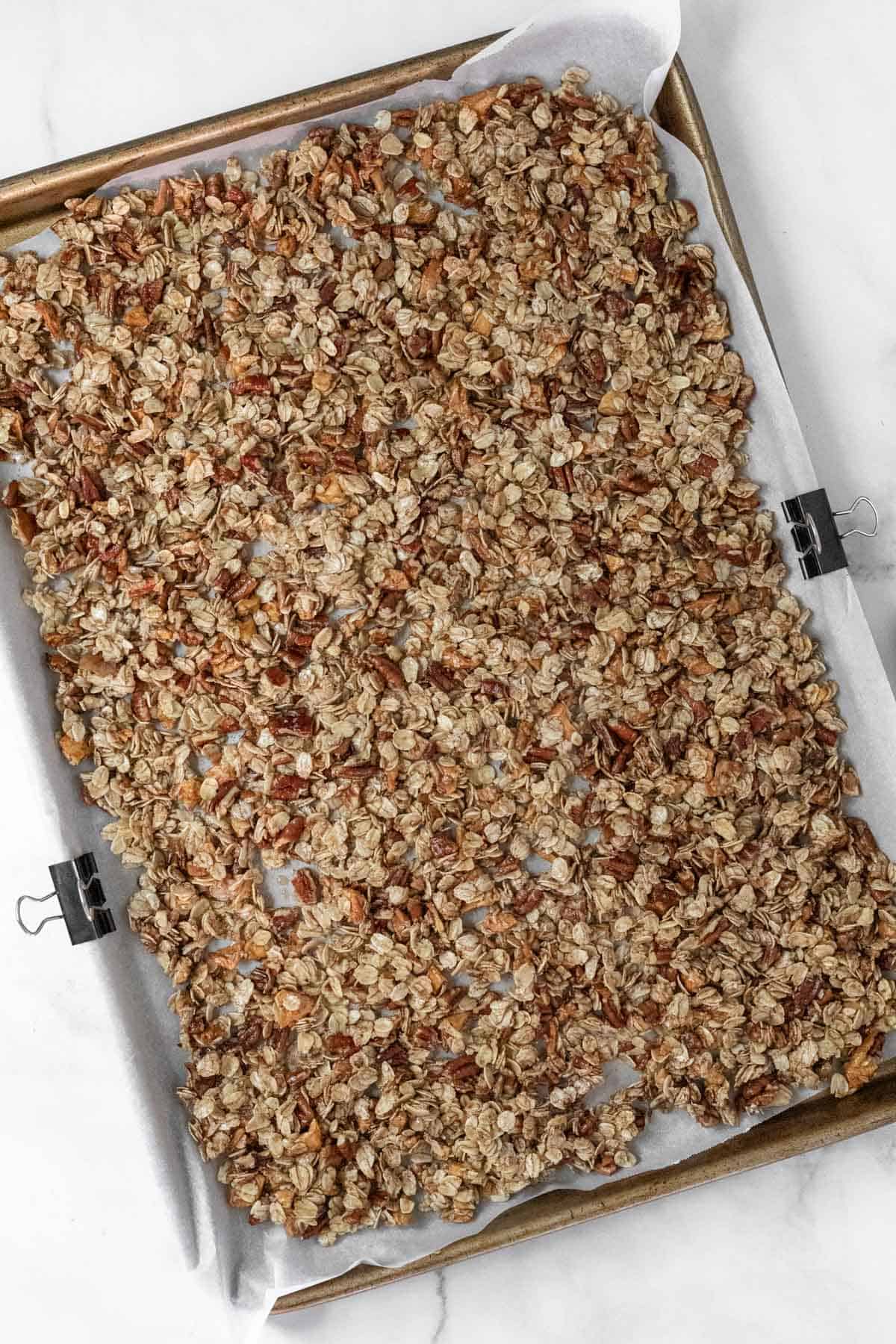 Granola ingredients spread out on a baking sheet before going in the oven.