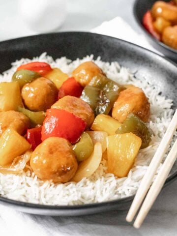 Sweet and sour chicken meatballs with stir fried peppers, onions, and pineapple on a bed of white rice.