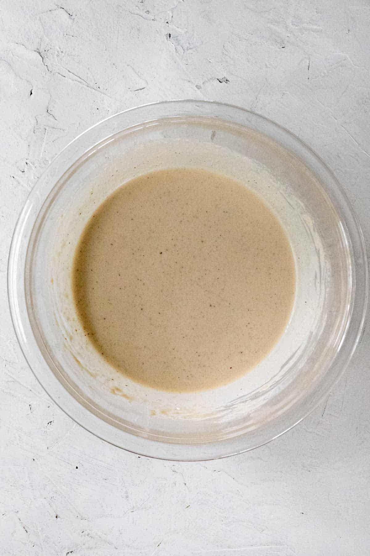 Lemon tahini sauce in a glass mixing bowl.