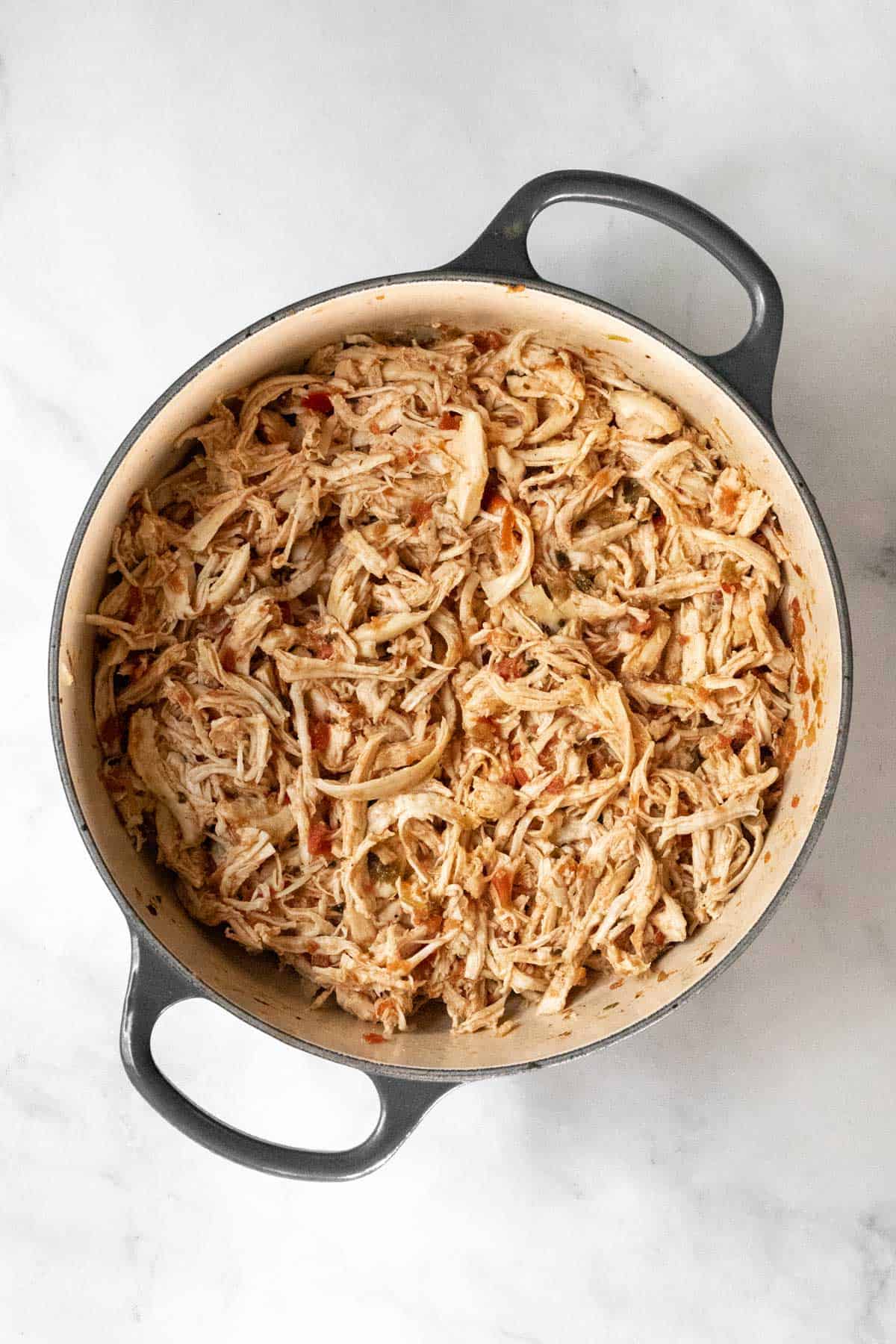 Shredded taco chicken in a dutch oven.