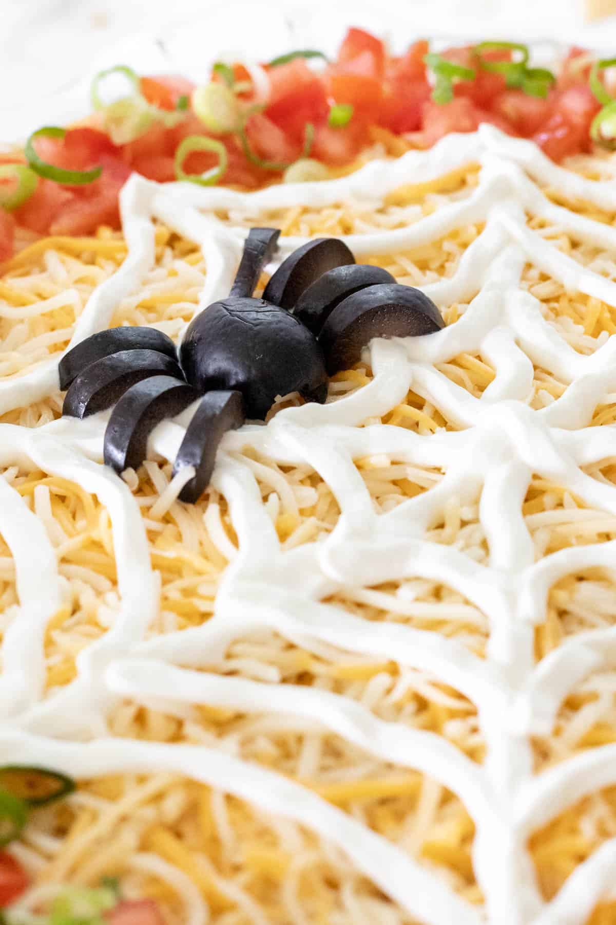 A closeup view of a black olive spider on top of the sour cream spiderweb.