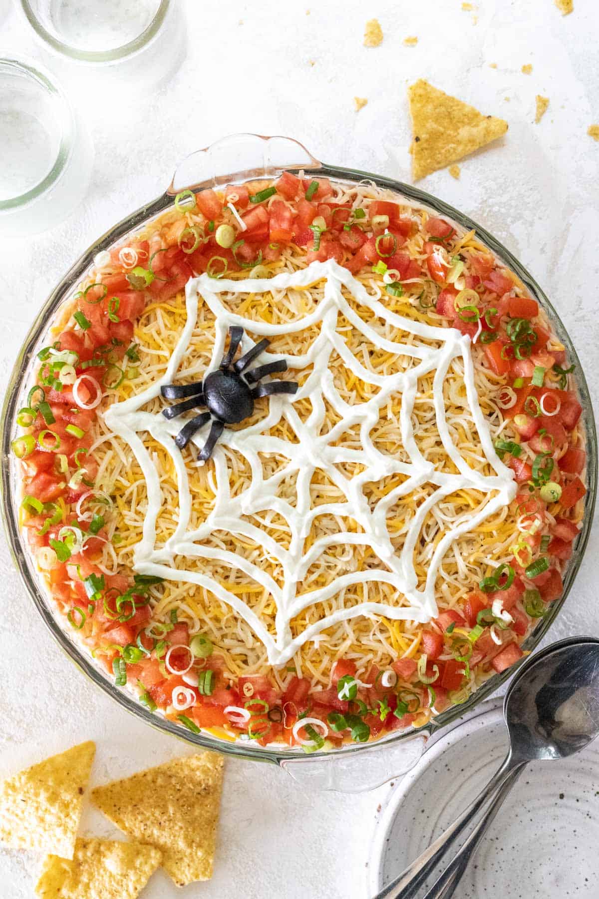 Spooky 7 layer Halloween taco dip in a large pie dish with chips around it.