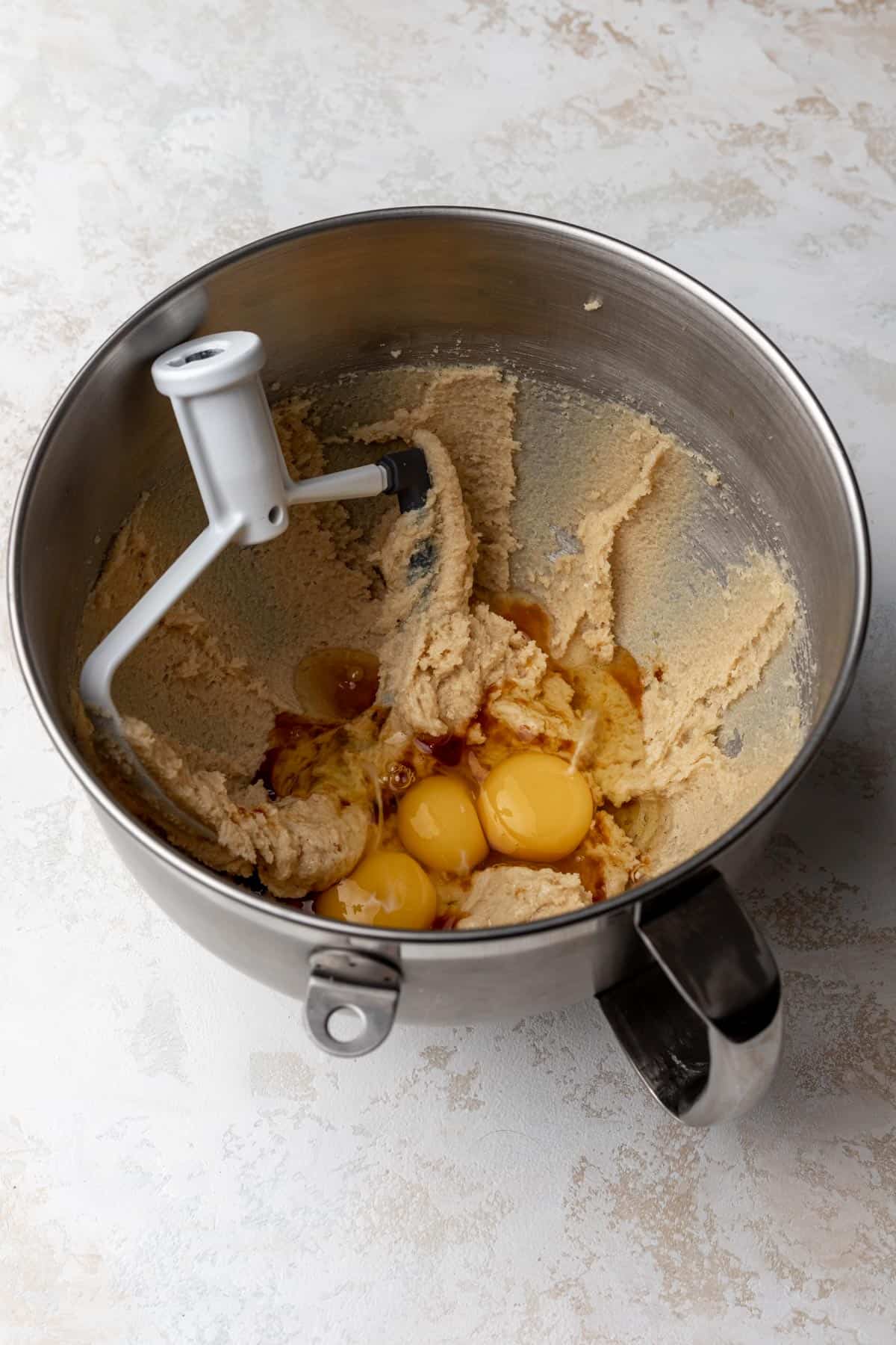 A mixing bowl with eggs and vanilla added to creamed butter and sugars.