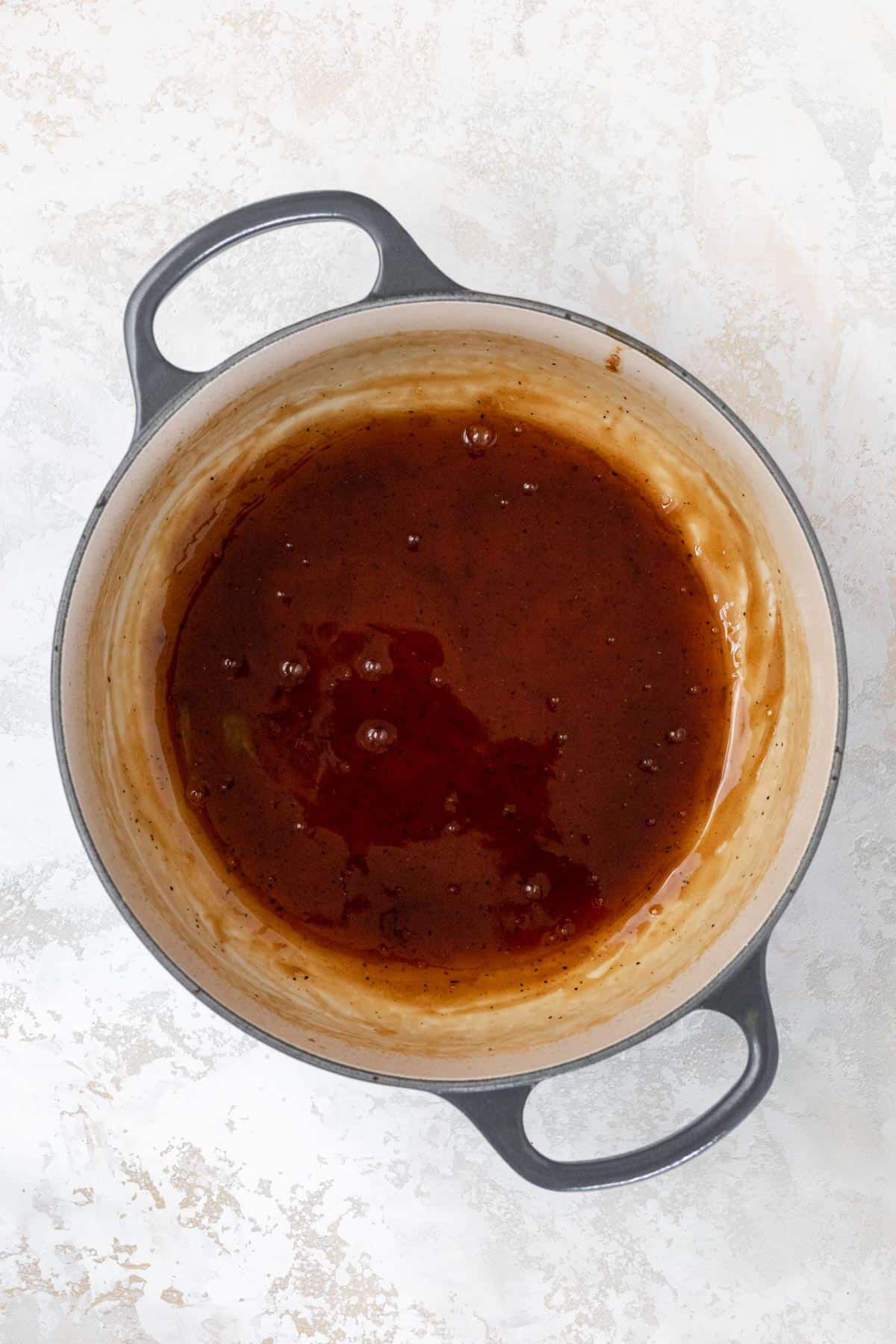 Reduced honey bourbon glaze in a large pot.