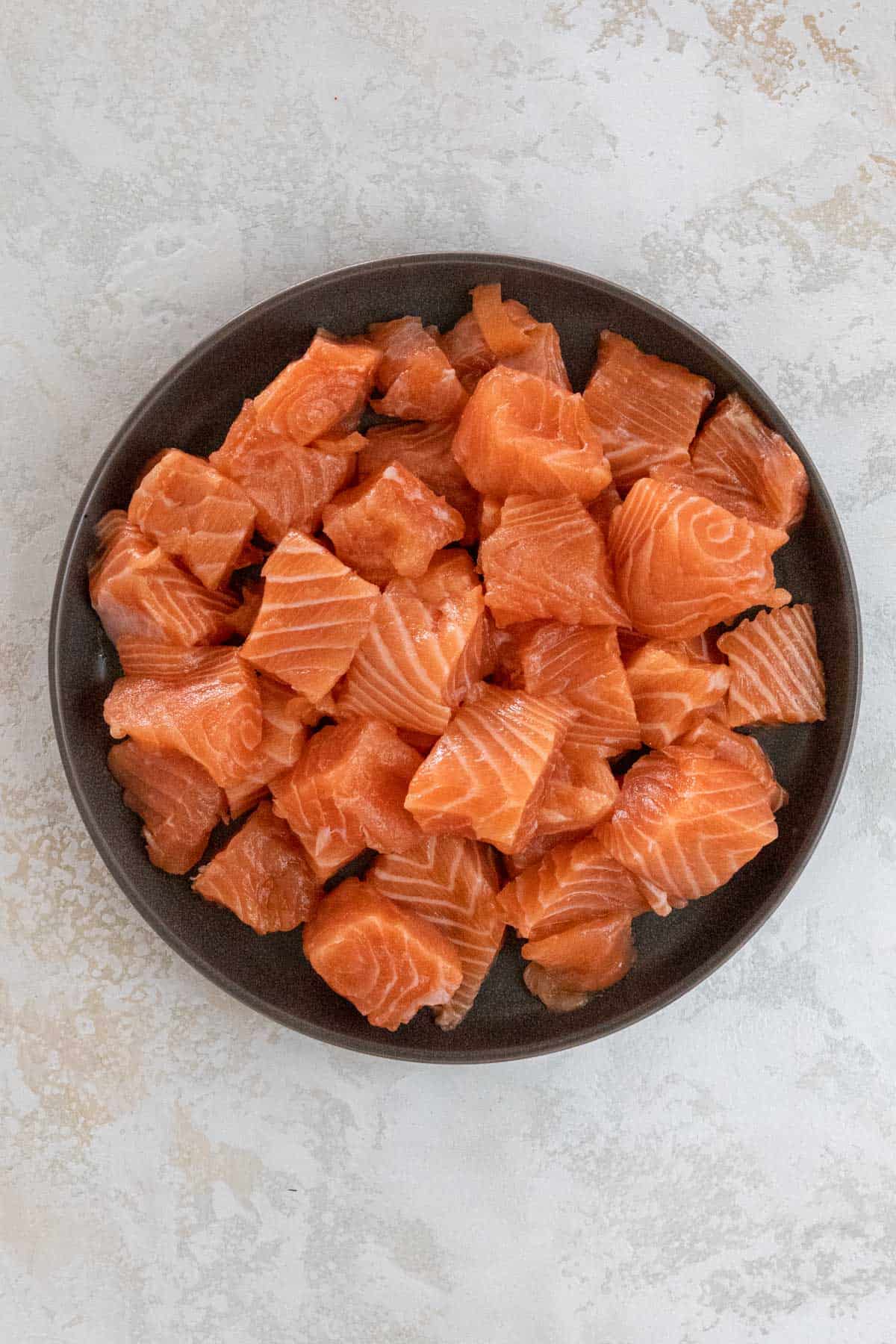 Cubed salmon in a black bowl.