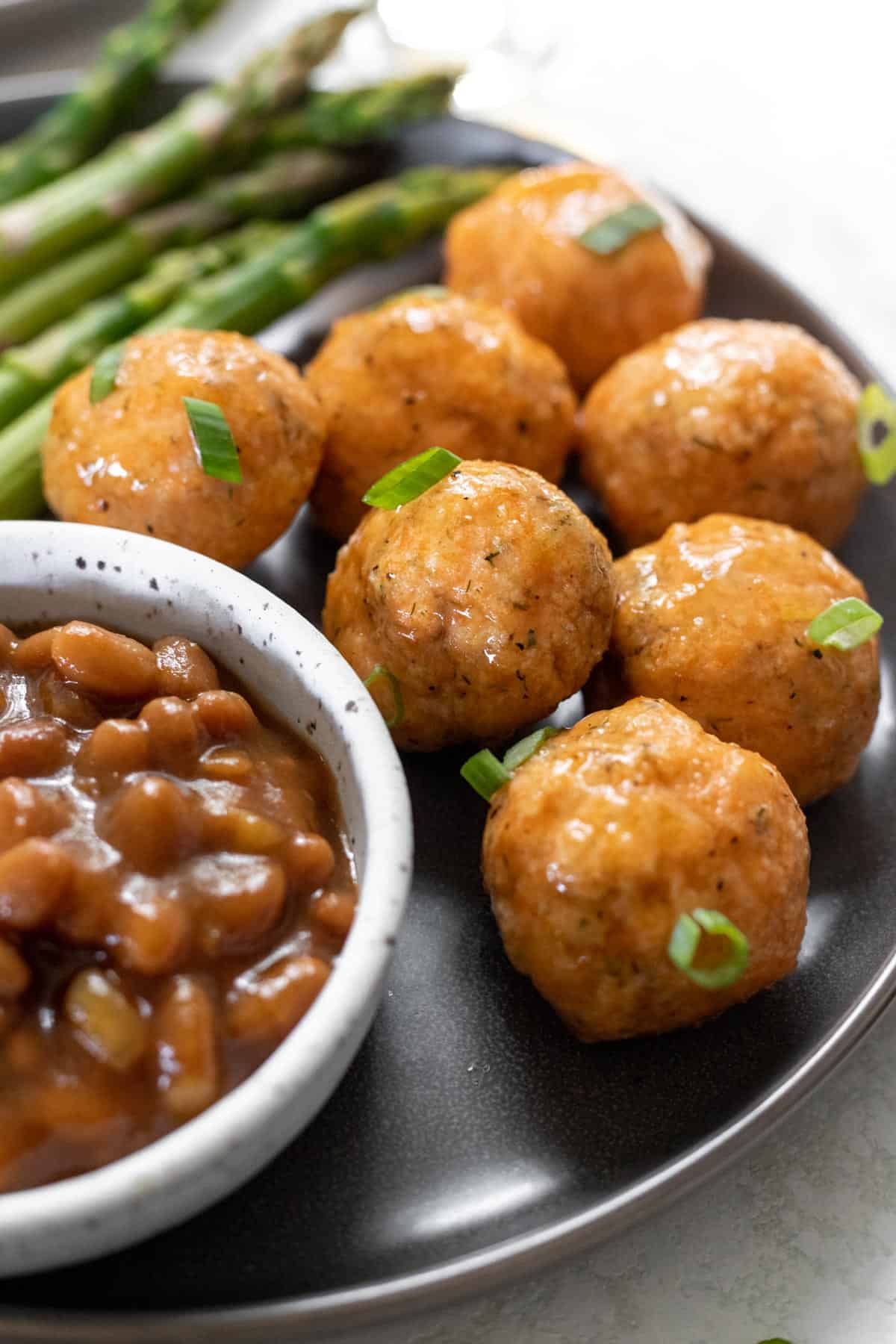 A closeup view of baked bourbon glazed salmon meatballs garnished with scallions.