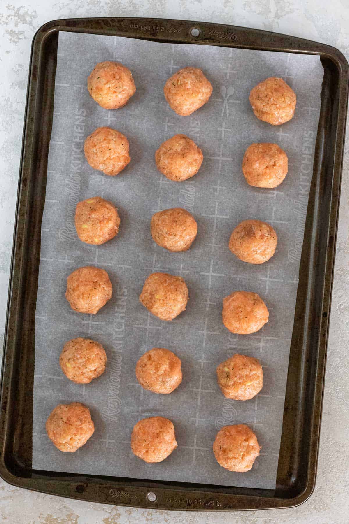 Raw salmon meatballs on a sheet pan.