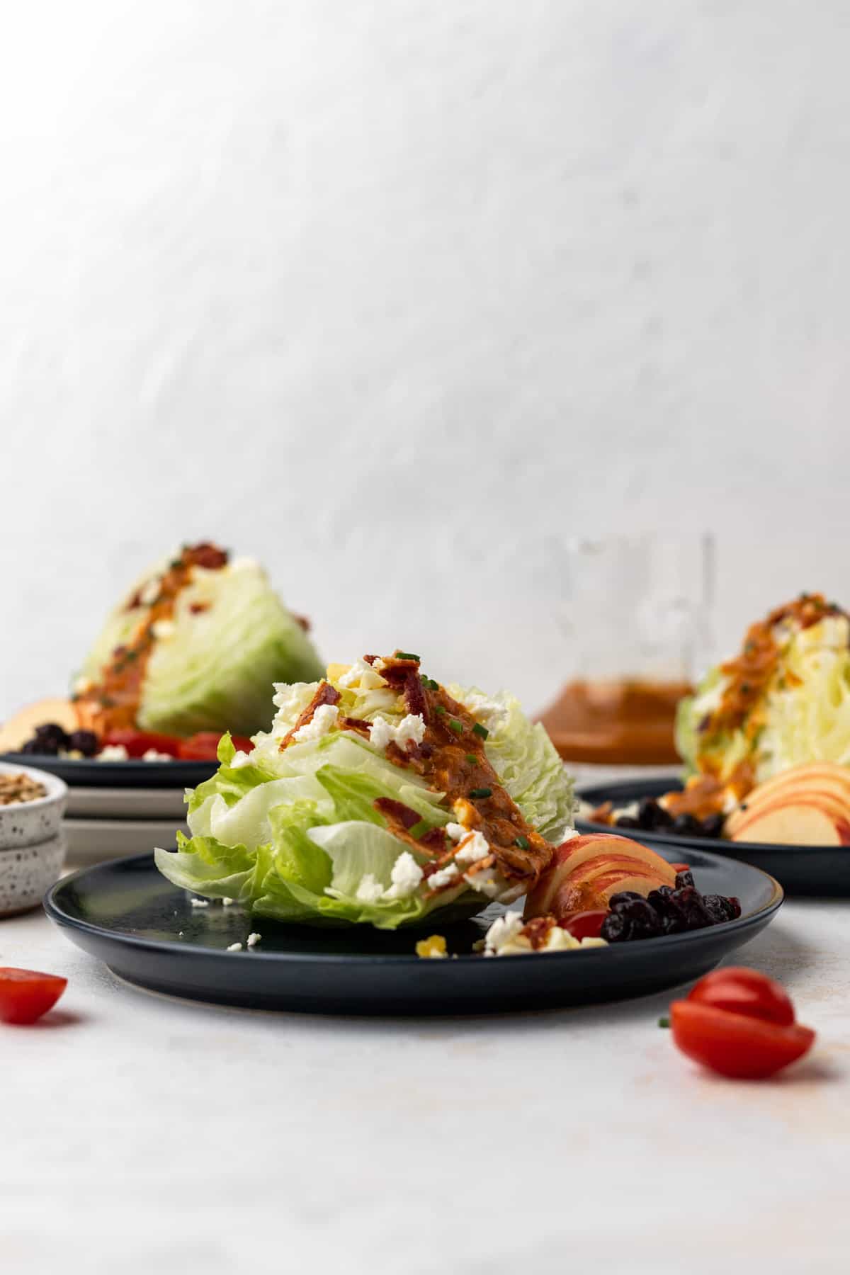 Pumpkin salad dressing drizzled over 3 wedge salads with salad toppings around them.