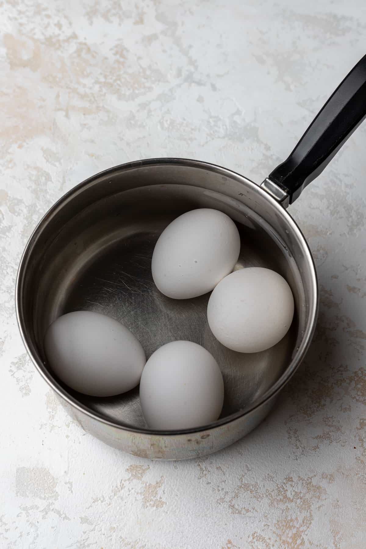 Eggs covered with water in a saucepan.